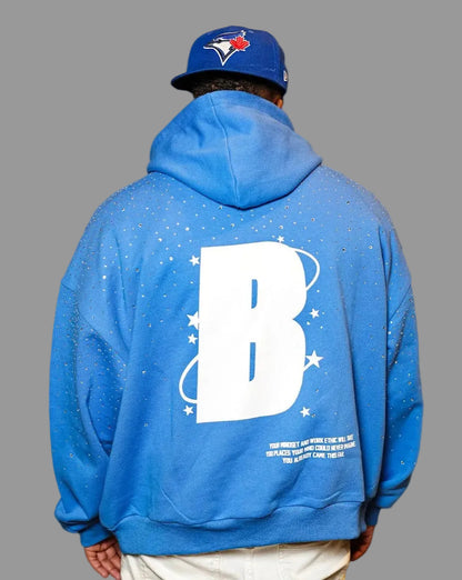Person wearing a blue hoodie with a large white letter 'B' on the back, standing against a white background.